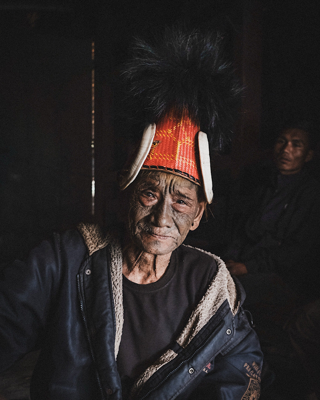 Guerrier Naga au visage couvert de tatouages coiffé d'un chapeau traditionnel à cornes et plumes