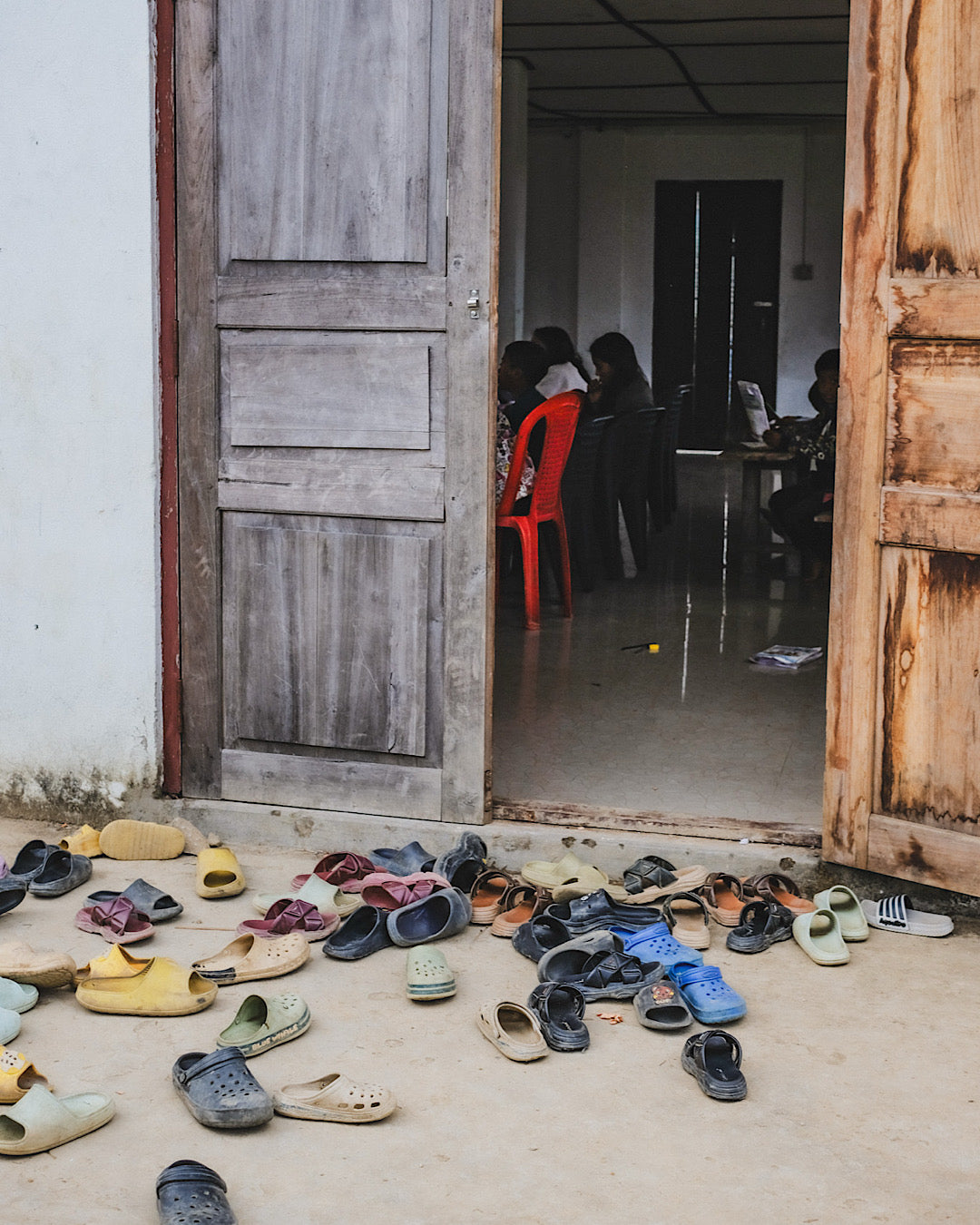 amoncellement de chaussures d'enfants devant la porte d'une école dans un village du Nagaland