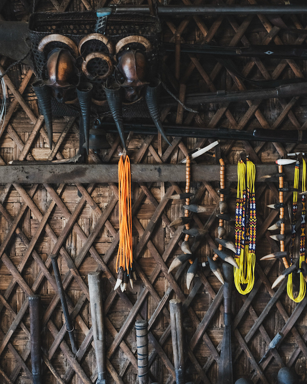 Mur de maison du Nagaland en bambou sur lequel sont accrochés des bijoux traditionnels et des armes