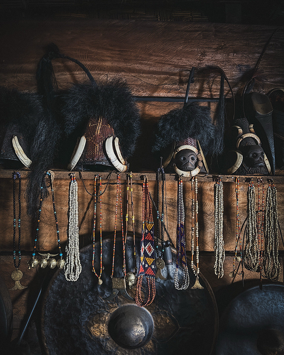 Étagère dans une maison Naga sur laquelle reposent des chapeaux traditionnels en bambou, cornes et plumes ainsi que des bijoux