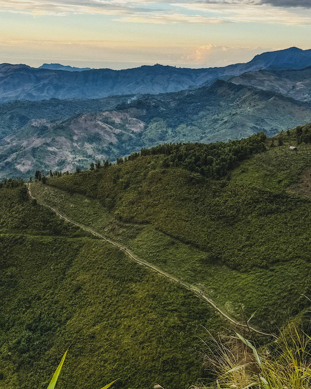 Vue de la vallée Naga avec un chemin qui serpente sur le flanc de montagne sur lequel on peut voir en petit les travailleurs qui rentrent le soir